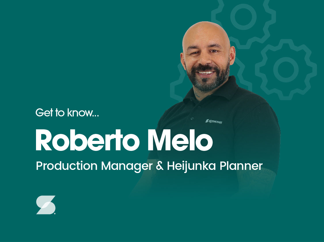 Dark green background with a faded silhouette of a cog and a photo of Roberto Melo. The text reads "Get to know Roberto Melo Production Manager and Heijunka Planner" and has a small Sigwaves icon in the bottom left