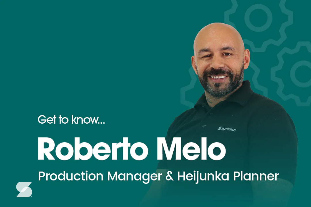 Dark green background with a faded silhouette of a cog and a photo of Roberto Melo. The text reads "Get to know Roberto Melo Production Manager and Heijunka Planner" and has a small Sigwaves icon in the bottom left
