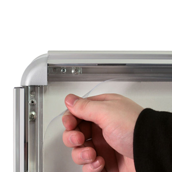 Hand holding a clear plastic sheet against a metallic frame on a white background