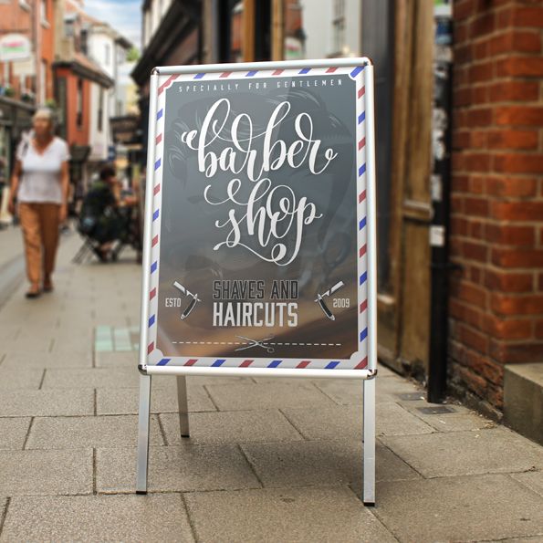 Barber shop sign on a sidewalk with people walking in the background