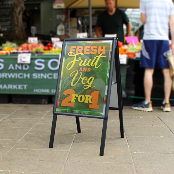 Outdoor market scene with a sign advertising fresh fruit and vegetables 2 for 1.