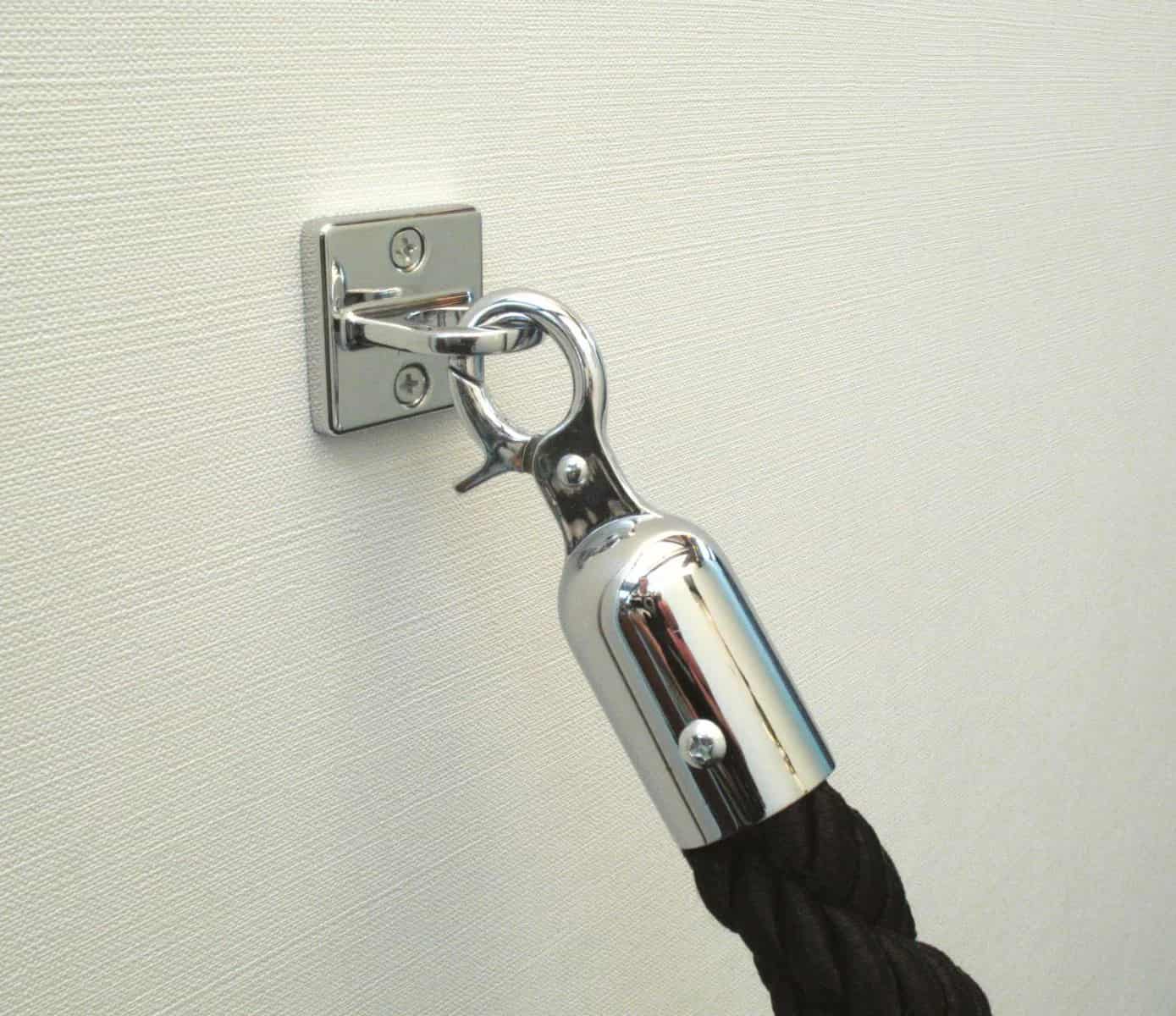 Metal cleat with a rope attached to a textured wall